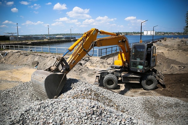 Yellow backhoe picking up stones.